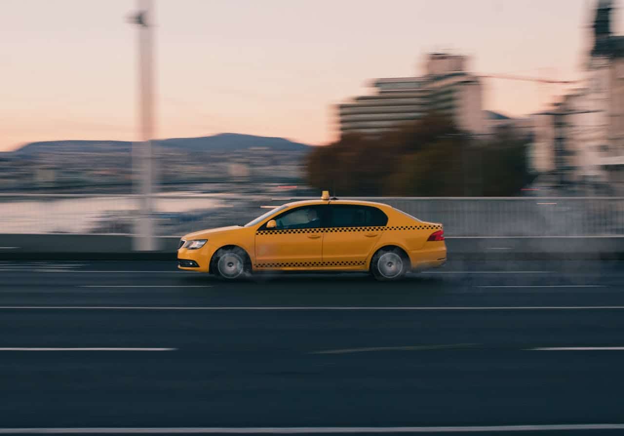 Mastering the First Impression: Your intriguing post title goes here Yellow taxi speeding along a Budapest street at dusk, capturing urban motion.